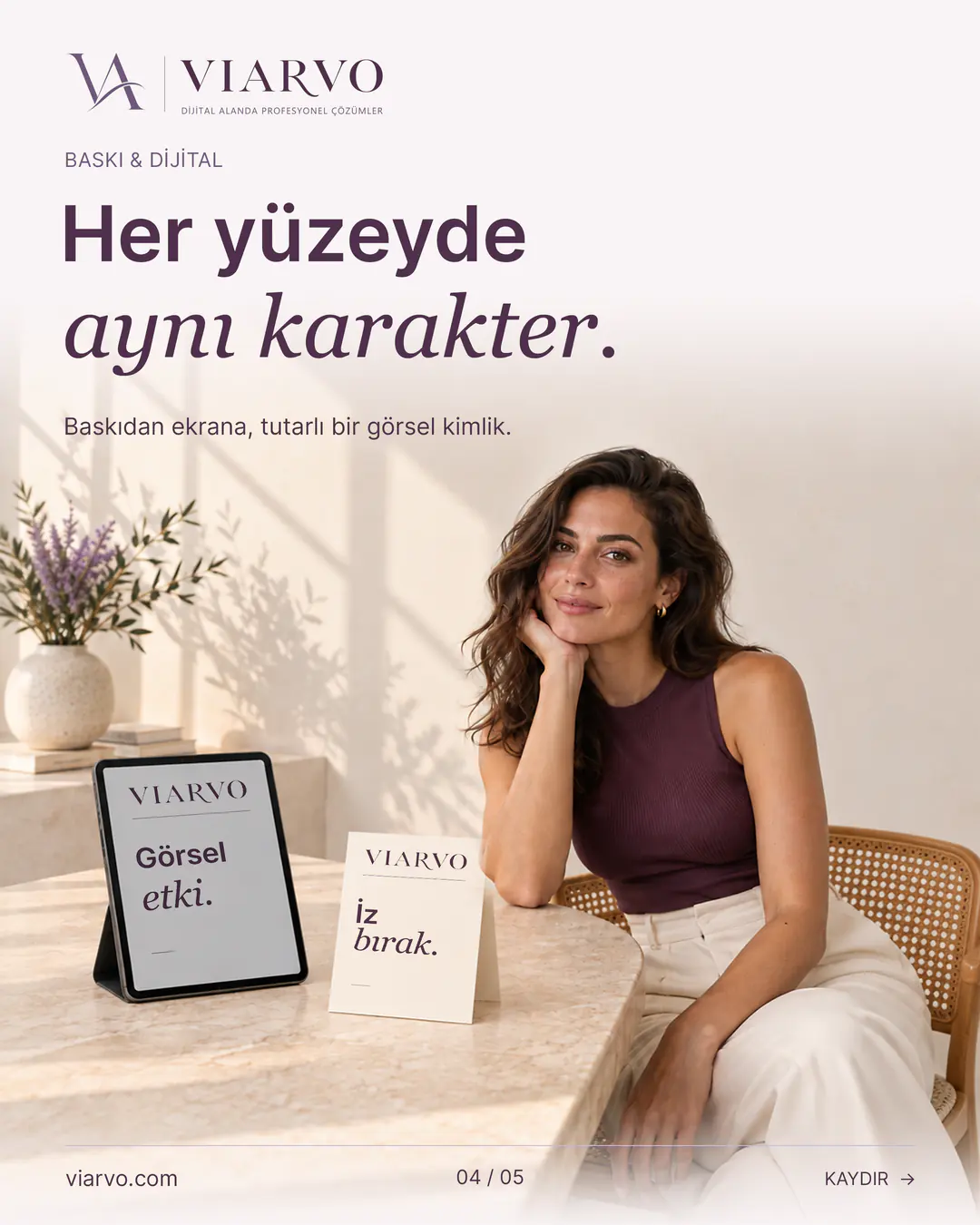 “Her yüzeyde aynı karakter.” başlıklı VIARVO sayfası. Mürdüm üst ve krem pantolonlu yetişkin kadın, gün ışıklı stüdyoda taş masanın yanında oturuyor. Masadaki öne dönük tablet ekranında ve ayakta duran kalın kartta VIARVO'nun krem ve mürdüm görsel dili uygulanmış.